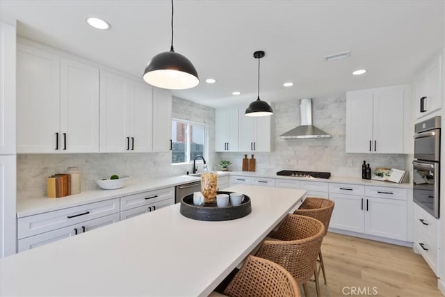 24531 Bunbury Dr, Lake Forest, CA 92630 - kitchen featuring visible vents, a breakfast bar, wall chimney exhaust hood, white cabinets, and backsplash