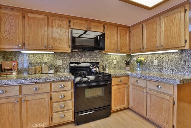 27720 St Bernard Ln, Lake Arrowhead, CA 92352 - kitchen featuring brown cabinetry, light wood-style floors, tasteful backsplash, light stone counters, and black appliances