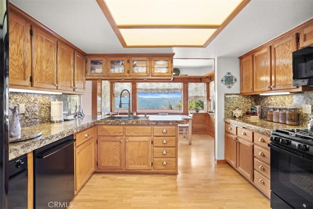 27720 St Bernard Ln, Lake Arrowhead, CA 92352 - kitchen with a peninsula, light wood finished floors, a sink, and black appliances