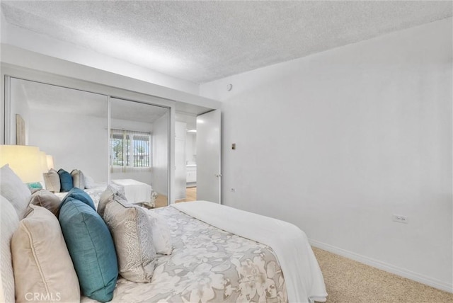 bedroom with a textured ceiling, light carpet, and baseboards