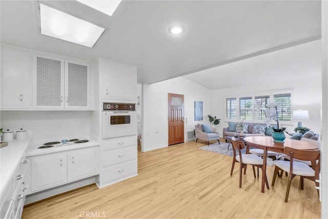 dining space with light wood-style floors and lofted ceiling