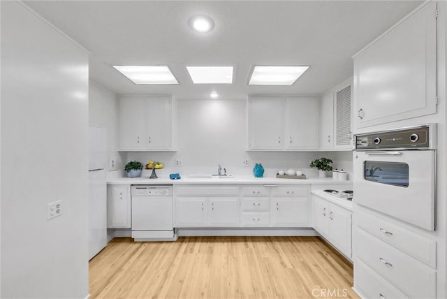 kitchen featuring light countertops, white cabinets, light wood-style floors, and white appliances
