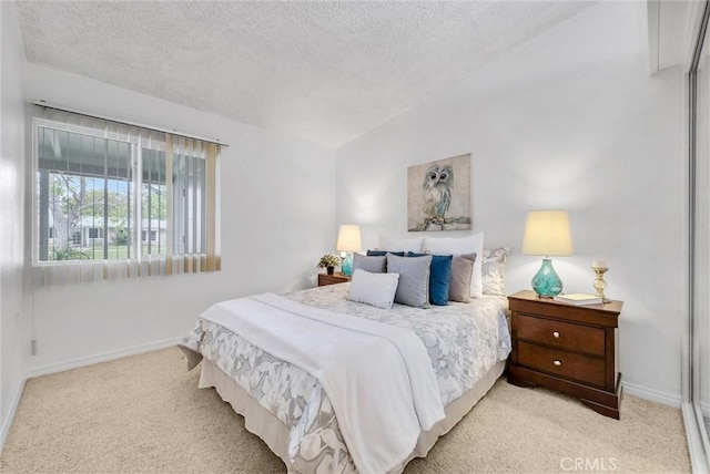 bedroom with baseboards, light carpet, and a textured ceiling