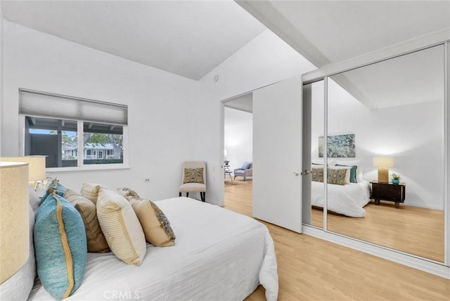 bedroom with vaulted ceiling, light wood-style flooring, and a closet