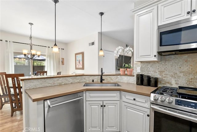 655 Via Colinas, Thousand Oaks, CA 91362 - kitchen featuring appliances with stainless steel finishes, a sink, a peninsula, decorative backsplash, and a chandelier