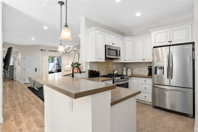 655 Via Colinas, Thousand Oaks, CA 91362 - kitchen with appliances with stainless steel finishes, a peninsula, backsplash, white cabinetry, and hanging light fixtures