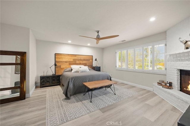 bedroom with visible vents, a brick fireplace, baseboards, light wood-style floors, and recessed lighting
