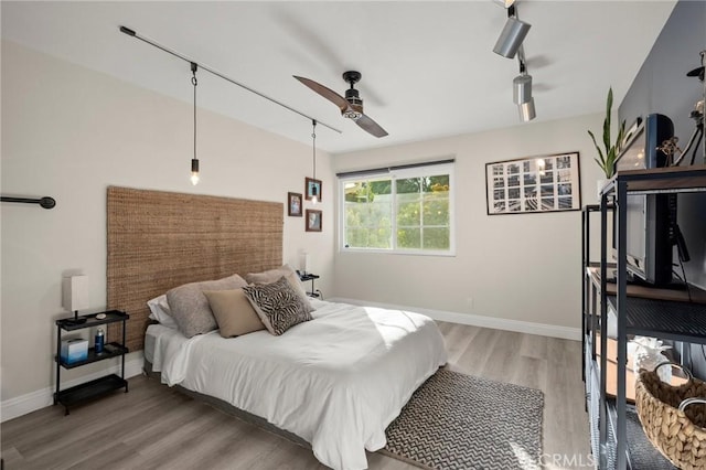 bedroom with rail lighting, baseboards, light wood finished floors, and ceiling fan