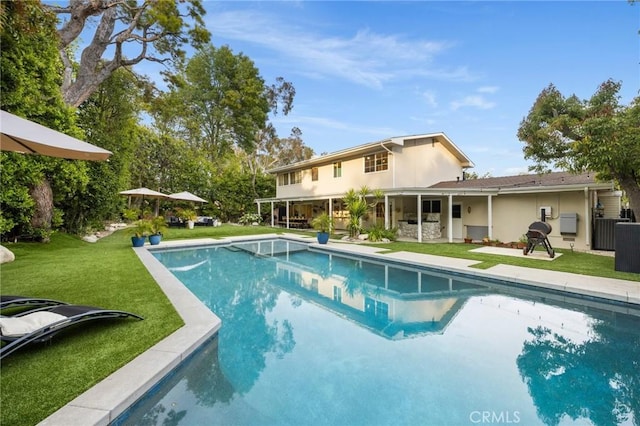 outdoor pool featuring a lawn