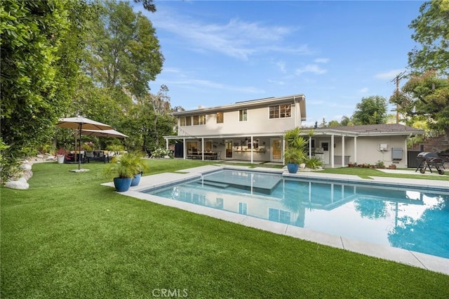 rear view of house featuring a lawn, an outdoor pool, stucco siding, and a patio