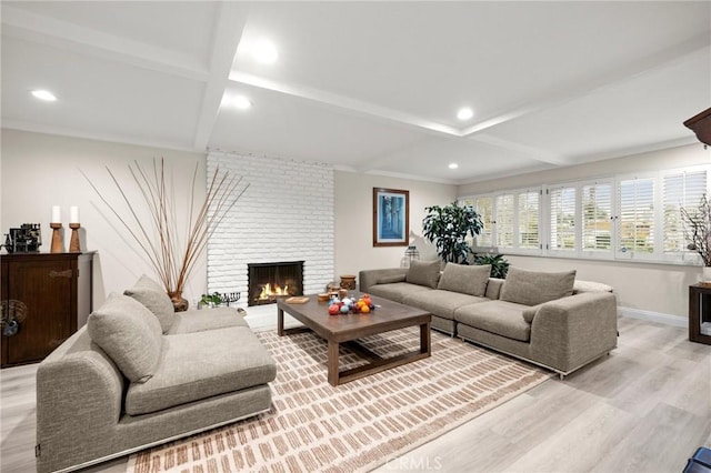 living area featuring light wood-style floors, baseboards, a brick fireplace, and beam ceiling