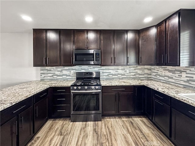 509 Kristi Ln, Blythe, CA 92225 - kitchen with dark brown cabinetry, appliances with stainless steel finishes, light stone counters, light wood-style floors, and tasteful backsplash
