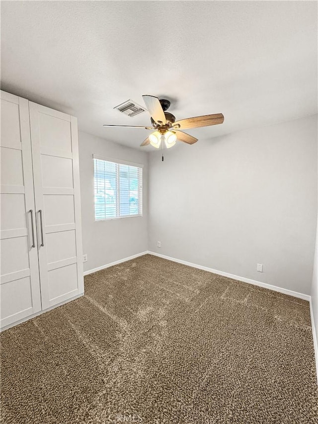 509 Kristi Ln, Blythe, CA 92225 - unfurnished bedroom with a ceiling fan, baseboards, visible vents, and dark colored carpet