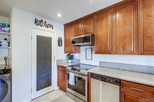 kitchen featuring brown cabinetry, light tile patterned floors, washer / dryer, stainless steel appliances, and recessed lighting