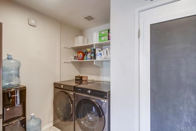 washroom with laundry area, visible vents, washing machine and dryer, baseboards, and tile patterned floors