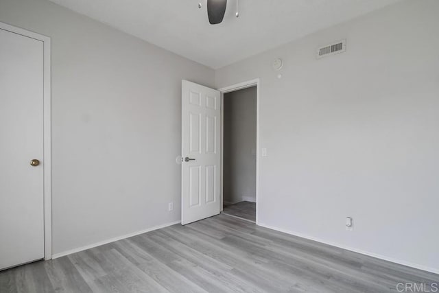 empty room featuring baseboards, ceiling fan, visible vents, and wood finished floors