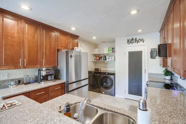 kitchen featuring brown cabinetry, a sink, washing machine and dryer, and stainless steel appliances