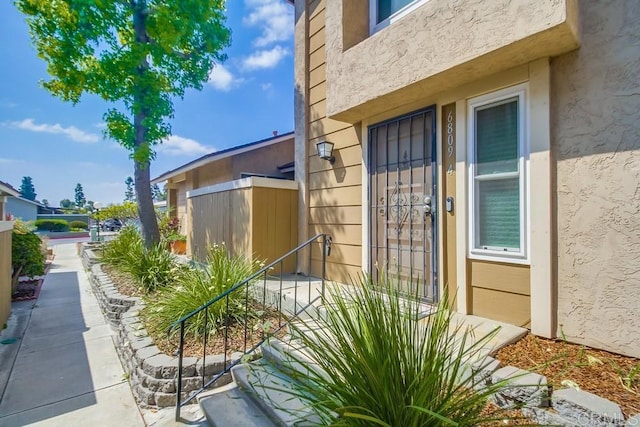 entrance to property with stucco siding and fence
