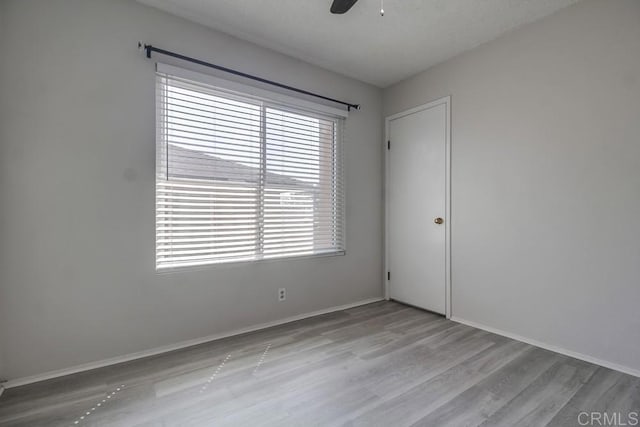 empty room featuring baseboards, ceiling fan, and wood finished floors