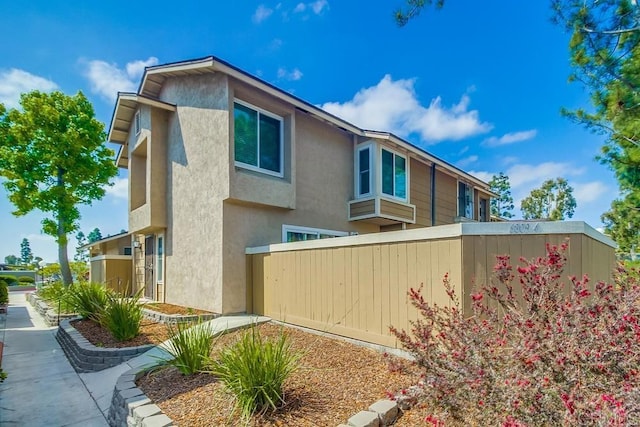 view of home's exterior with fence and stucco siding