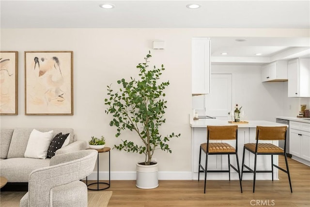 living room with recessed lighting, light wood-style flooring, baseboards, and a tray ceiling
