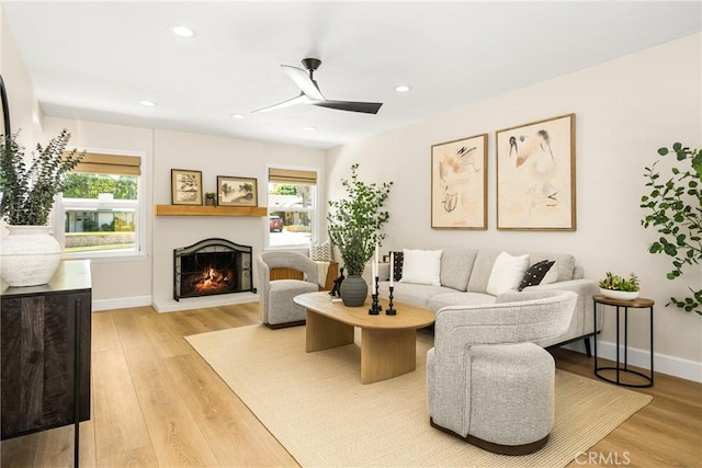 living room featuring a healthy amount of sunlight, a lit fireplace, and wood finished floors