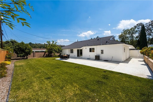 back of property with central AC, stucco siding, a fenced backyard, a patio area, and a yard