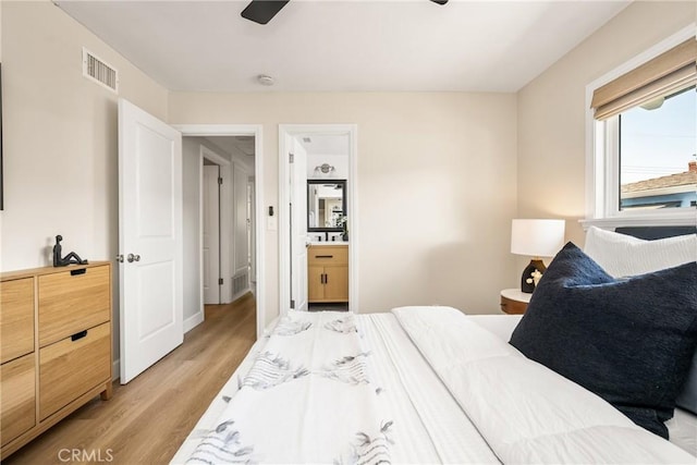 bedroom featuring ensuite bath, light wood-style flooring, and visible vents