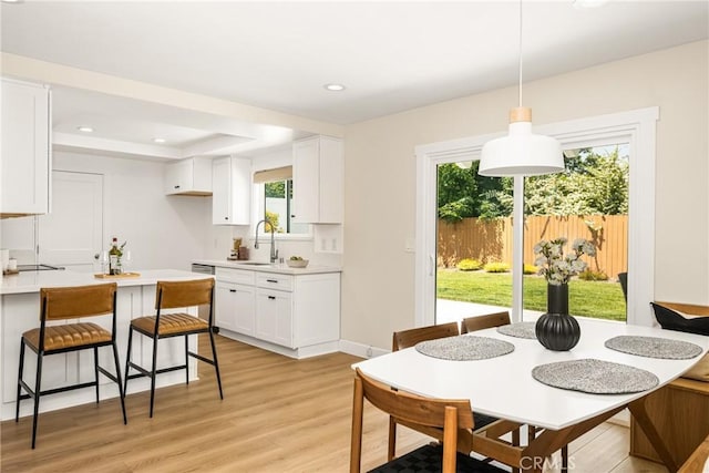 dining space with recessed lighting, a tray ceiling, and light wood-type flooring