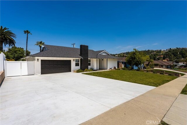 view of front facade featuring fence, an attached garage, concrete driveway, and a front lawn