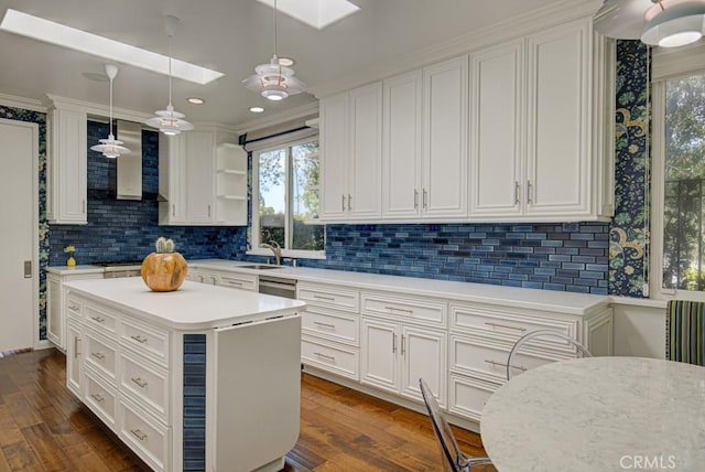 5594 Avenida Sosiega W Unit B, Laguna Woods, CA 92637 - kitchen with a skylight, white cabinets, wall chimney range hood, and a sink