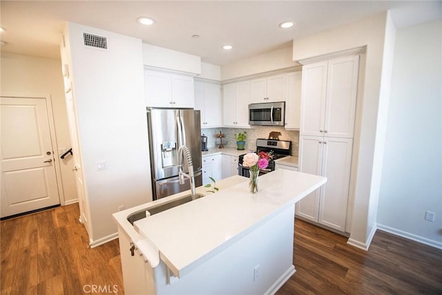 kitchen with visible vents, dark wood-style flooring, white cabinets, backsplash, and stainless steel appliances