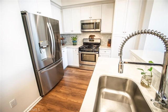 kitchen with decorative backsplash, appliances with stainless steel finishes, wood finished floors, a sink, and light countertops