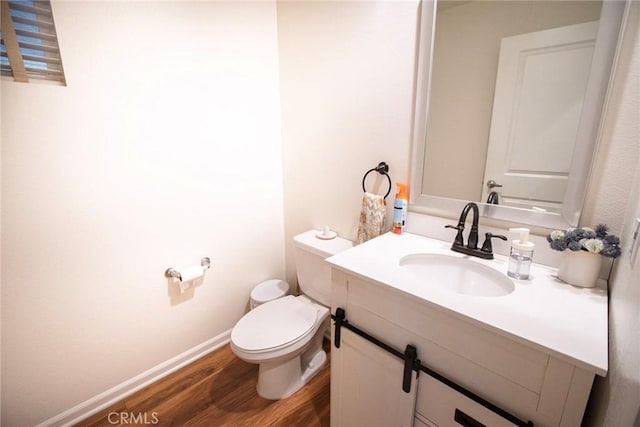 bathroom with vanity, baseboards, wood finished floors, and toilet