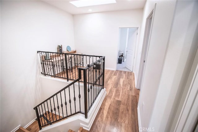 stairway featuring a skylight, baseboards, recessed lighting, and wood finished floors