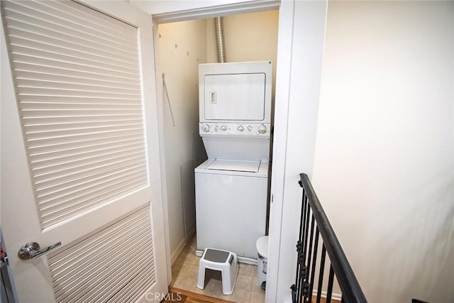 clothes washing area featuring baseboards, laundry area, tile patterned floors, and stacked washer and clothes dryer