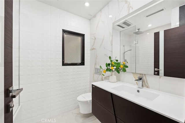 full bathroom with visible vents, tile walls, a tile shower, vanity, and toilet