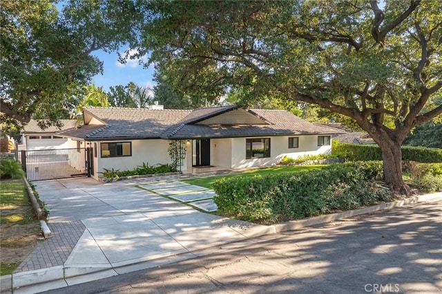 single story home featuring a gate, stucco siding, and driveway