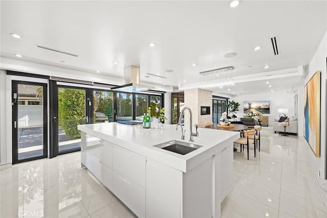 kitchen with modern cabinets, a large island with sink, a sink, open floor plan, and white cabinetry