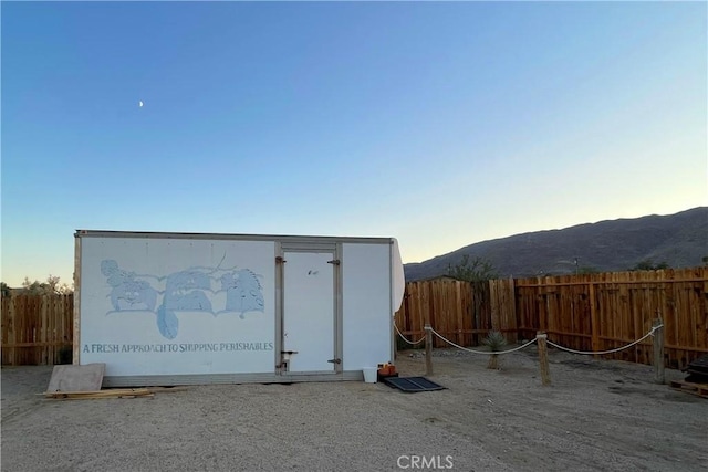 outdoor structure at dusk featuring a fenced backyard and a mountain view