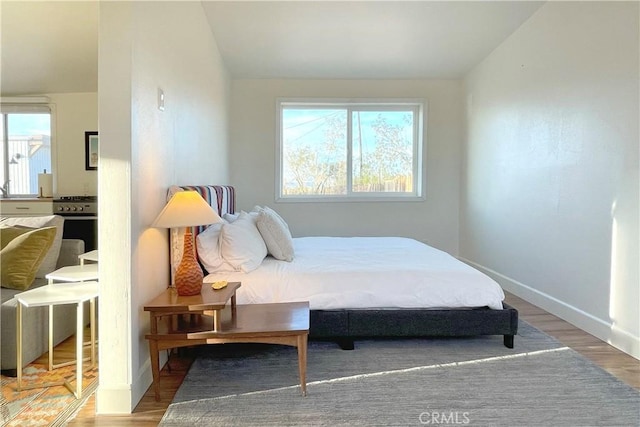 bedroom featuring baseboards, wood finished floors, and lofted ceiling