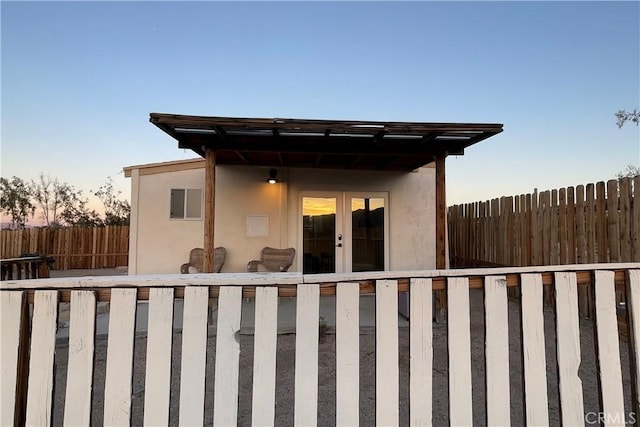 exterior space featuring stucco siding, fence, and french doors
