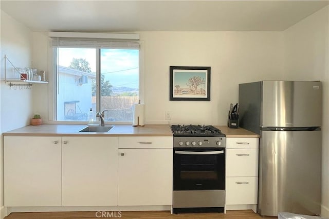 kitchen featuring light countertops, a sink, white cabinetry, and stainless steel appliances