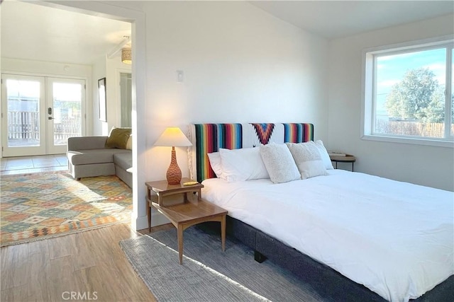 bedroom featuring french doors, wood finished floors, access to outside, and multiple windows