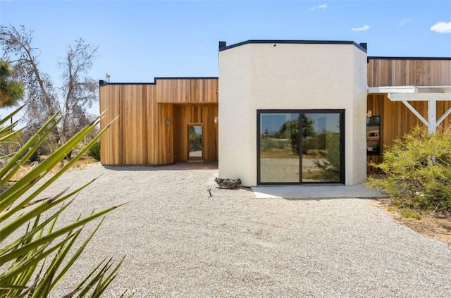 back of property with stucco siding and fence
