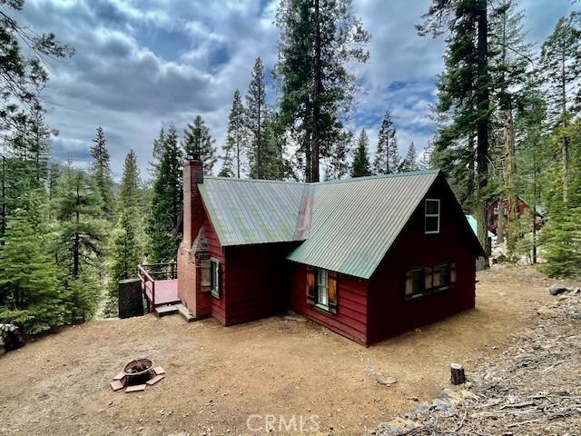 38784 Aspen Ln, Mineral, CA 96063 - view of side of home featuring a fire pit, a chimney, a forest view, and metal roof