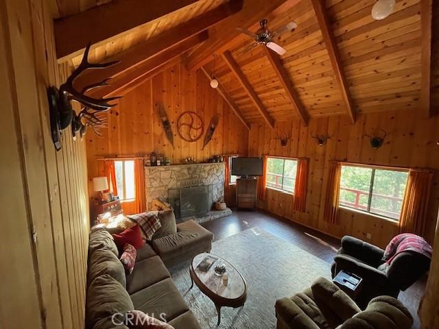 38784 Aspen Ln, Mineral, CA 96063 - living room with wood walls, wood finished floors, a stone fireplace, wooden ceiling, and ceiling fan