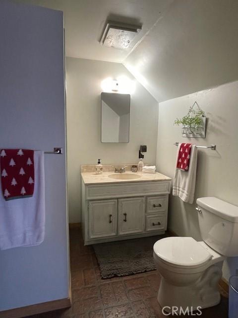 38784 Aspen Ln, Mineral, CA 96063 - bathroom with vaulted ceiling, toilet, vanity, brick patterned flooring, and baseboards
