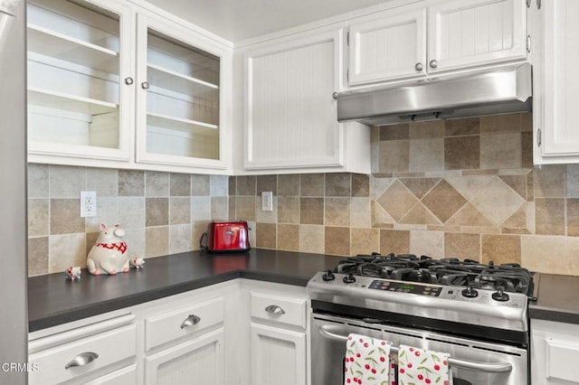 kitchen with dark countertops, tasteful backsplash, gas stove, under cabinet range hood, and white cabinetry