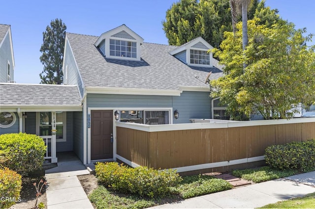 view of front of house featuring fence and a shingled roof